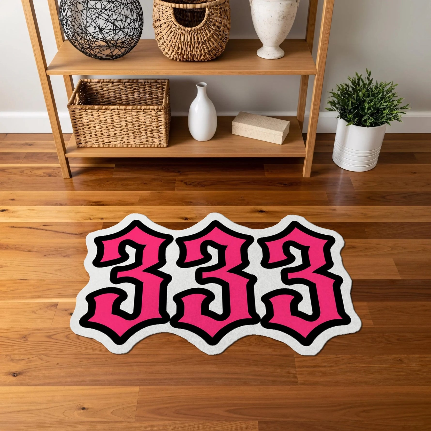 Kalın ve kıvrımlı yazı karakteriyle oluşturulmuş “333” tipografisi içeren, pembe, beyaz ve siyah renk kombinasyonuna sahip, yüksek kontrastlı, pop kültür ve graffiti stilini yansıtan figürlü halı yüzeyi.
