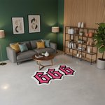 Canlı pembe renkte “666” rakamlarından oluşan, kalın siyah dış kontur ve beyaz iç hatla çevrelenmiş, köşeleri yumuşatılmış, kıvrımlı ve kalın font yapısına sahip, graffiti ve pop art stilinde tasarlanmış, yüksek kontrastlı tipografik figür kesim halı.
