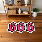 Graffiti etkili tipografik halı; canlı pembe tonlarda büyük “666” rakamları, net beyaz iç hat ve kalın siyah dış konturla çevrelenmiş, pop art estetiğinde, güçlü kontrast sunan ve dikkat çekici figür kesim tasarıma sahip baskı.
