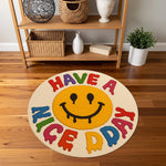 Renkli tipografi ile çevrelenmiş sarı gülen yüz motifi içeren yuvarlak halı; ortada damlama efektli smiley, dış halkada “HAVE A NICE DAY” mesajı, pop kültür estetiğinde, canlı renk paletli ve çizgi film stilinde grafik kompozisyon.
