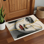 Sanatsal figürlü dikdörtgen halı; yüz figürü üzerinde ilerleyen altın tonlu çatlak detaylarıyla dikkat çeker. Porselen yüzey hissi veren desen yapısı, estetik ve kırılganlık temasını yansıtır. Çarpıcı, karakteristik ve dekoratif bir halı modelidir.
