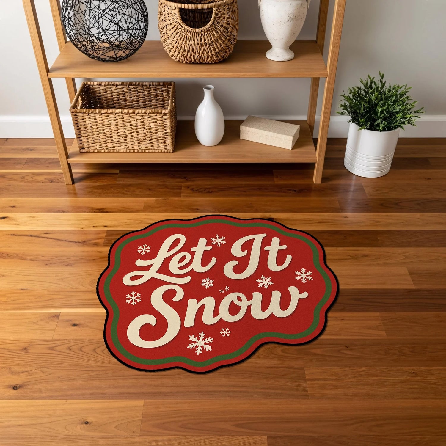 Özel formda kesilmiş Noel temalı halı; merkezde kıvrımlı beyaz “Let It Snow” tipografisi, etrafında simetrik kar tanesi motifleri, kırmızı ana zemin ve yeşil çerçeve şeridiyle oluşturulmuş, yüksek kontrastlı grafik baskı tasarımı.
