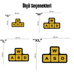 Minimal ve teknoloji temalı grafik tasarım halı, WASD harflerinden oluşan yön tuşu düzenini temsil eden geometrik kompozisyon içerir. Siyah zemin üzerinde sarı kare alanlar bulunur ve her karede büyük W, A, S, D tipografisi yer alır. Oyun kültürünü yansıtan sade ve güçlü kontrastlı modern dekoratif halı tasarımıdır.