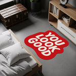 Motivasyon temalı tipografi halısı; kırmızı zemin üzerinde yumuşak köşeli, kalın beyaz harflerle yazılmış “YOU LOOK GOOD” metni, eğlenceli ve modern grafik anlayışıyla oluşturulmuş, özel şekilli dekoratif yüzey tasarımı.
