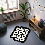 Beyaz büyük punto yazı karakteriyle oluşturulmuş “YOU LOOK GOOD” metnini taşıyan, siyah arka planlı, yumuşak konturlu, kalın dış hatlara sahip, motivasyon temalı, çağdaş tipografik tasarıma sahip özel formlu halı deseni.
