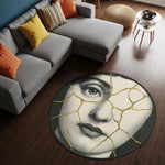 Yuvarlak formda tasarlanmış, siyah zemin üzerine işlenmiş klasik kadın yüzü illüstrasyonuna sahip dekoratif halı. Yüz figürü porselen doku hissi veren çatlak desenlerle bölünmüş, çatlaklar altın rengi kintsugi stilinde vurgulanmıştır. Sanatsal ve modern tasarım.
