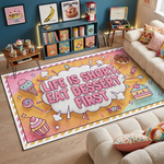 Pop art ve illüstratif stilde tasarlanmış modern dekoratif halı, merkezde büyük tipografi ile yazılmış “LIFE IS SHORT EAT DESSERT FIRST” metni bulunan çizgi roman tarzı patlama kompozisyonuna sahiptir. Zeminde turuncu ve pembe tonlar kullanılmış, çevresinde dondurma, cupcake, donut, şeker ve tatlı illüstrasyonları yer alan grafik tasarım halı.