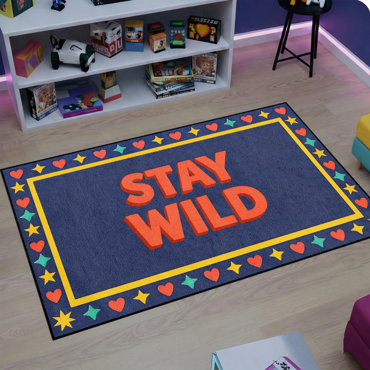 Modern ve grafik stil halı, ortada STAY WILD yazısı içerir. Renkli kalp ve yıldız motifli çerçeve ile canlı ve dikkat çekici bir kompozisyon oluşturur.
