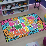 Retro pop art estetiğinde hazırlanmış sanatsal halı tasarımı, merkezde kalın ve eğlenceli tipografi ile oluşturulmuş “STAY WILD CHILD” yazısını barındırır. Arka planda çok renkli leopar desenli grafik yüzey bulunurken çevresinde stilize çiçek figürleri ve yıldız patlaması formlarıyla zenginleştirilmiş illüstratif kompozisyon yer alır.